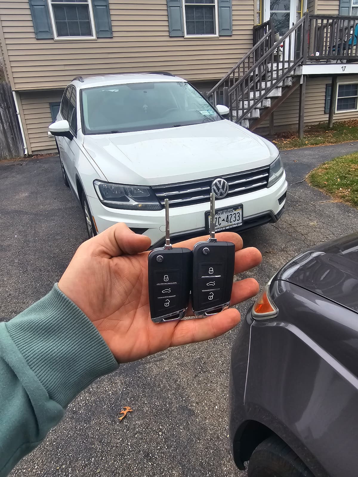 Two new Volkswagen Tiguan flip keys cut and programmed in front of a white Tiguan